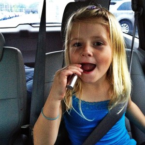 little girl putting on lipstick