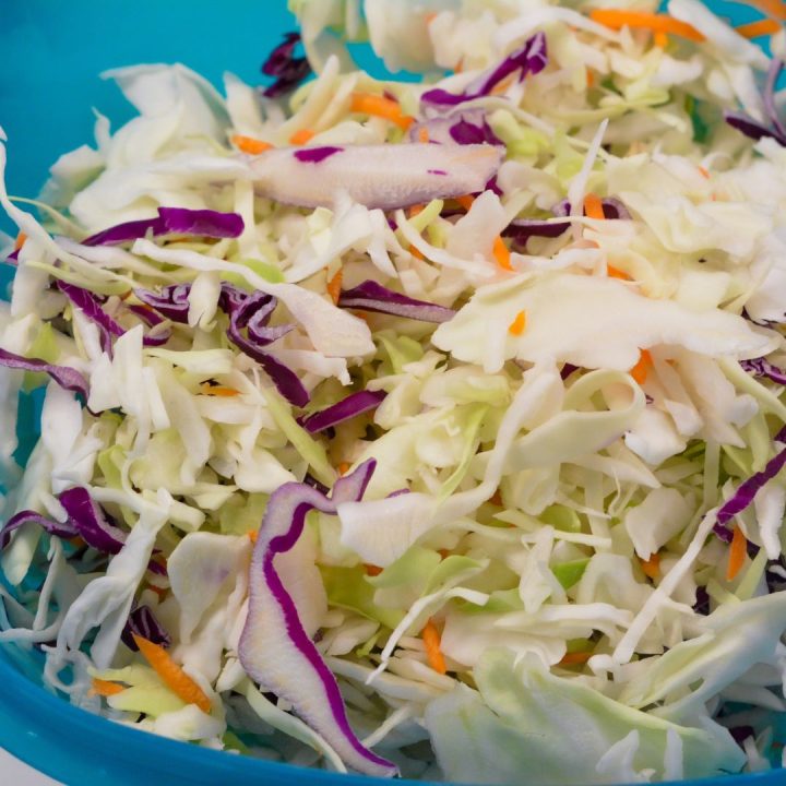 Combine the green and purple cabbage and grated carrots in a large bowl.