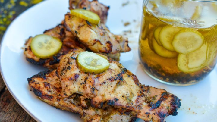 Pickle brined grilled chicken is made by marinating boneless, skinless chicken thighs in pickle juice, pickles, onions, garlic, peppercorns, and olive oil resulting in the juiciest grilled chicken.