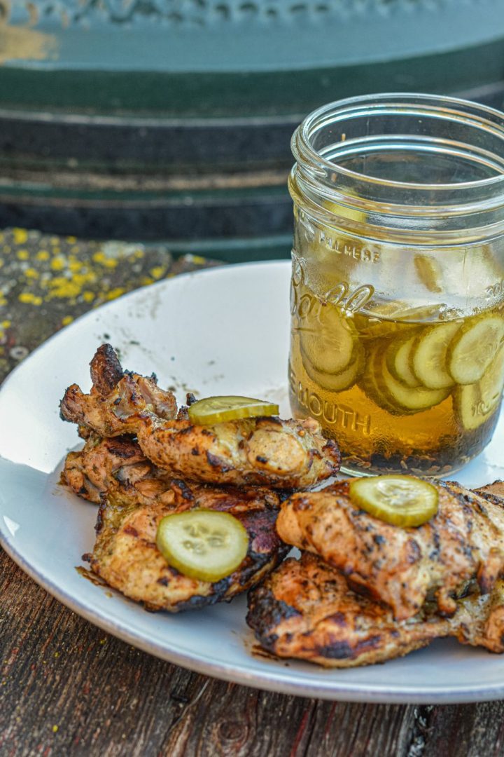 Pickle brined grilled chicken is made by marinating boneless, skinless chicken thighs in pickle juice, pickles, onions, garlic, peppercorns, and olive oil resulting in the juiciest grilled chicken.