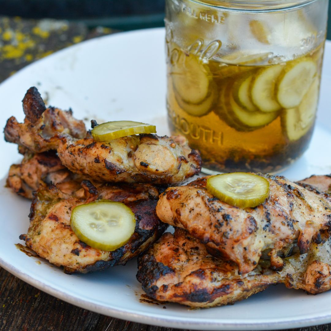 Pickle brined grilled chicken is made by marinating boneless, skinless chicken thighs in pickle juice, pickles, onions, garlic, peppercorns, and olive oil resulting in the juiciest grilled chicken.