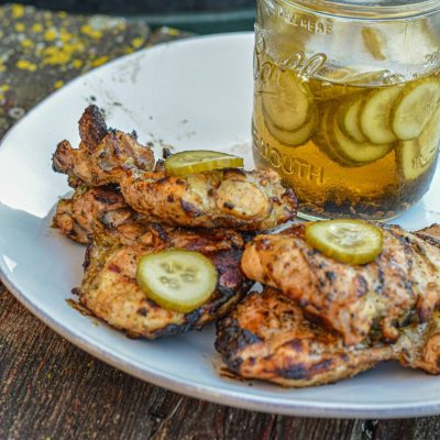 Pickle brined grilled chicken is made by marinating boneless, skinless chicken thighs in pickle juice, pickles, onions, garlic, peppercorns, and olive oil resulting in the juiciest grilled chicken.