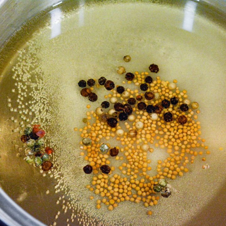 In a medium saucepan, combine the apple cider vinegar, water, sugar, kosher salt, whole mustard seeds, and whole peppercorns.