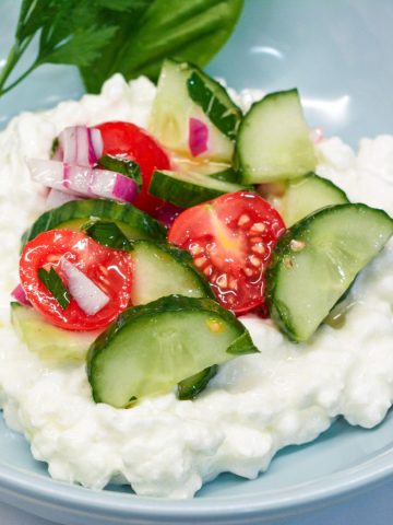 Spoon the cottage cheese into the bottom of a shallow bowl, and then scoop the cucumber salad over the top of it.