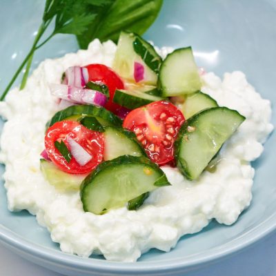 Spoon the cottage cheese into the bottom of a shallow bowl, and then scoop the cucumber salad over the top of it.