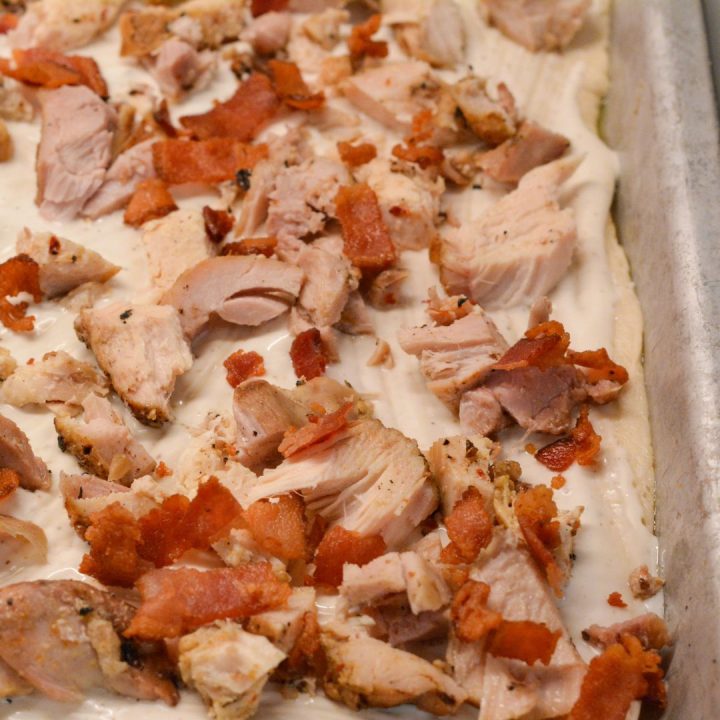 Scatter the shredded or diced cooked chicken over the ranch dressing. Sprinkle the crispy chopped bacon evenly over the pizza. Add the thinly sliced red onions for a bit of bite (optional).