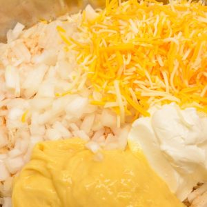 Mix Everything Together: In a large mixing bowl, combine the hash browns, cream of chicken soup, shredded cheddar cheese, sour cream, diced onion, melted butter, and black pepper. Stir until well combined.