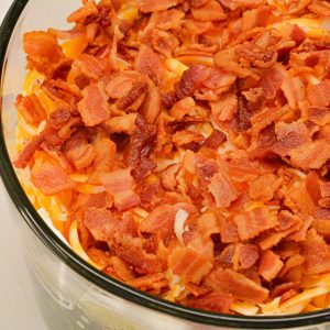 Finish the salad with salad dressing and then the shredded cheese and bacon.