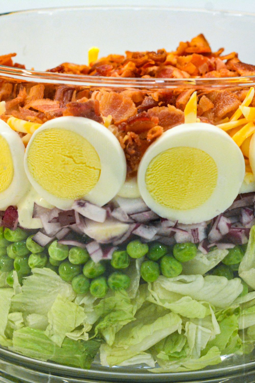 This easy 7-layer salad recipe is a crowd-pleaser with crisp romaine, peas, onions, bacon, eggs, cheese, and creamy dressing. Perfect for potlucks or make-ahead meals!