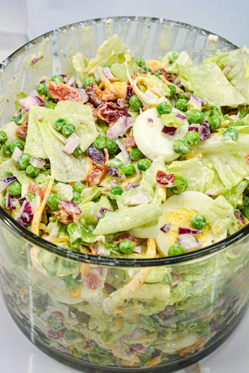 This easy 7-layer salad recipe is a crowd-pleaser with crisp romaine, peas, onions, bacon, eggs, cheese, and creamy dressing. Perfect for potlucks or make-ahead meals!