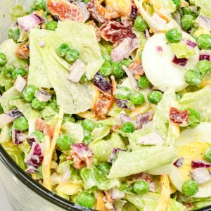 This easy 7-layer salad recipe is a crowd-pleaser with crisp romaine, peas, onions, bacon, eggs, cheese, and creamy dressing. Perfect for potlucks or make-ahead meals!