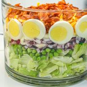 This easy 7-layer salad recipe is a crowd-pleaser with crisp romaine, peas, onions, bacon, eggs, cheese, and creamy dressing. Perfect for potlucks or make-ahead meals!