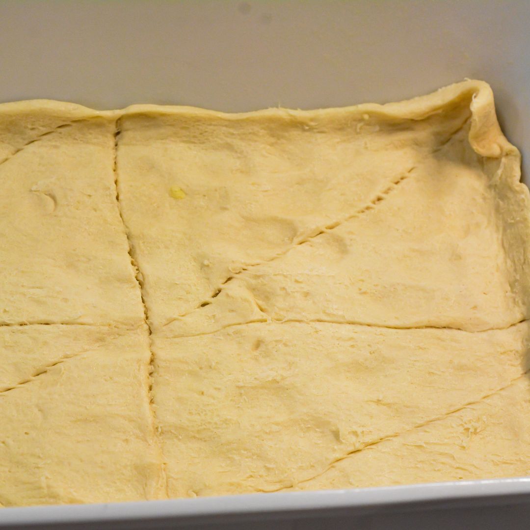 Layer the Crescent Roll Base - Unroll one can of crescent rolls and press the dough evenly into the bottom of your greased baking dish. Press the seams together. This layer adds a delicious, flaky texture to the casserole.