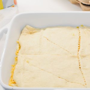 Add the Top Crescent Roll Layer - Unroll the second can of crescent rolls and place it over the top of the casserole.