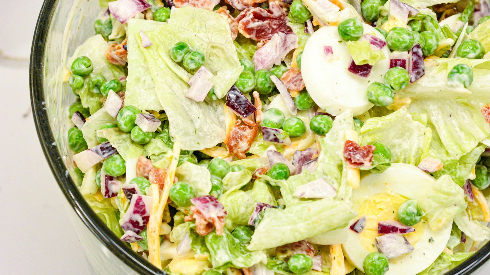 This easy 7-layer salad recipe is a crowd-pleaser with crisp romaine, peas, onions, bacon, eggs, cheese, and creamy dressing. Perfect for potlucks or make-ahead meals!